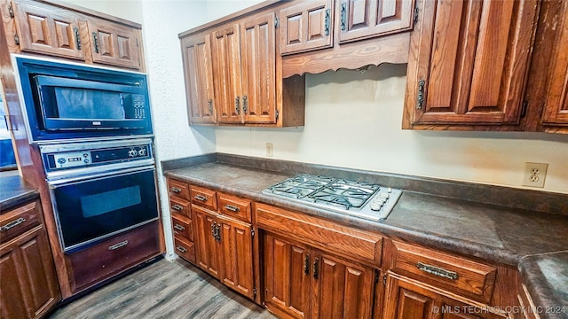 kitchen with built in microwave, stainless steel gas cooktop, oven, and light hardwood / wood-style floors