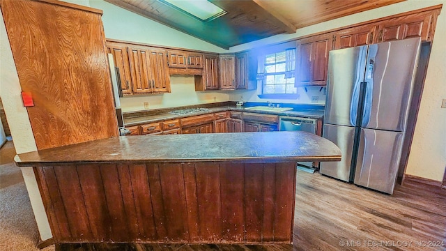 kitchen featuring vaulted ceiling, appliances with stainless steel finishes, sink, kitchen peninsula, and light hardwood / wood-style flooring