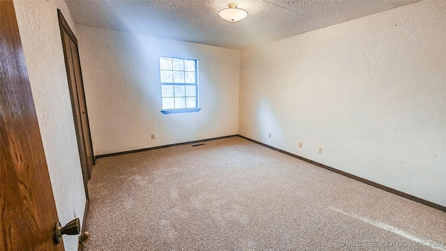 spare room featuring carpet floors and a textured ceiling