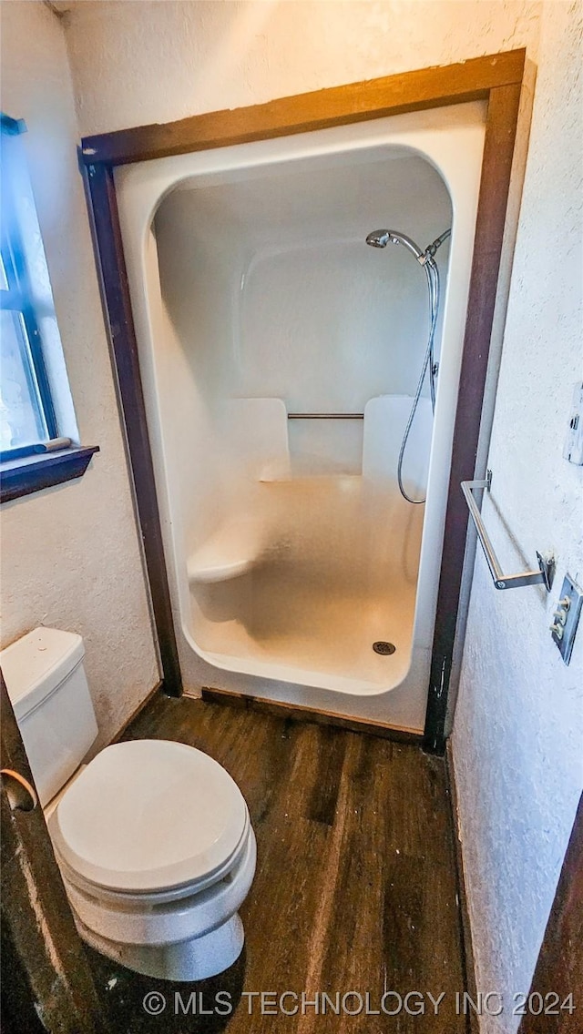 bathroom with hardwood / wood-style floors, a shower, and toilet