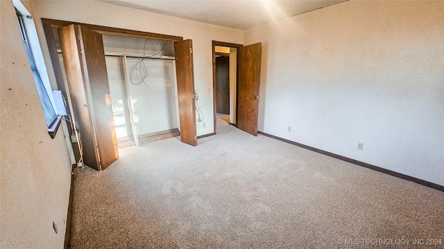 unfurnished bedroom featuring light colored carpet and a closet