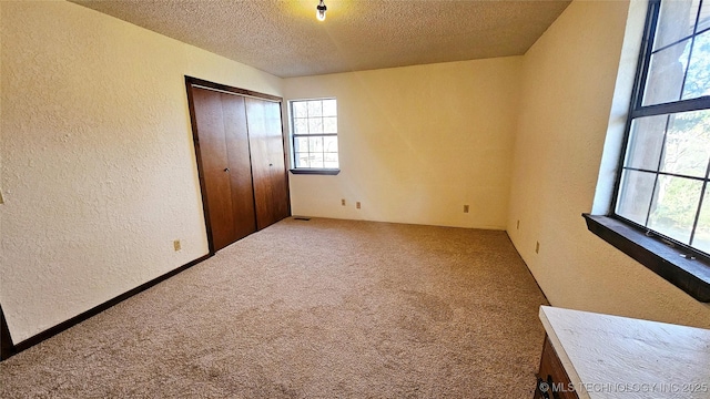 unfurnished bedroom featuring a closet, a textured ceiling, and carpet flooring