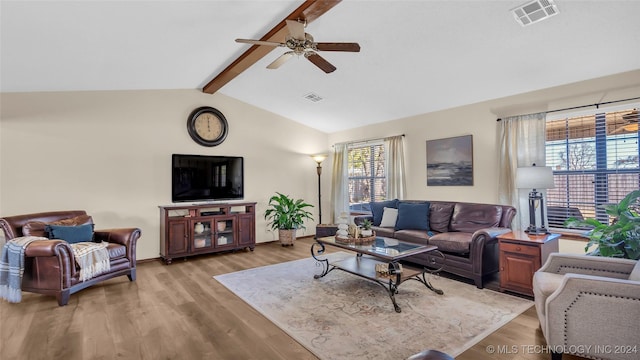 living room with a wealth of natural light, ceiling fan, lofted ceiling with beams, and light wood-type flooring