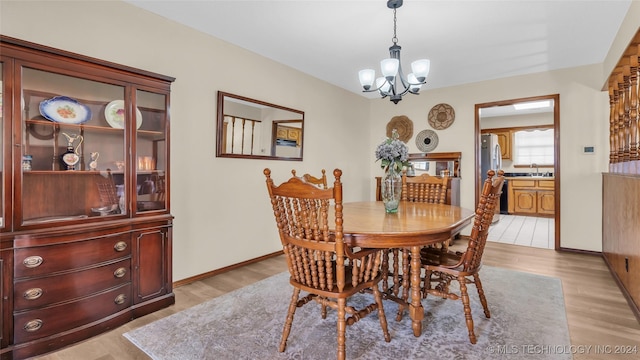 dining space featuring sink, a notable chandelier, and light wood-type flooring