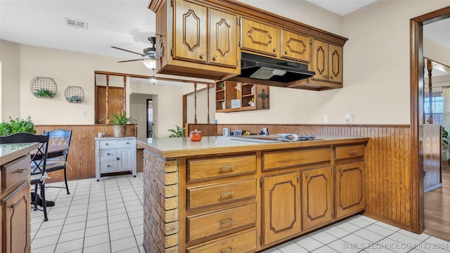 kitchen featuring white gas stovetop, wooden walls, ceiling fan, and light tile patterned flooring