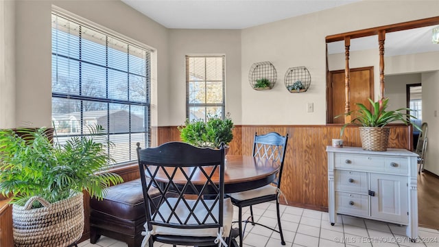 dining area with wood walls and light tile patterned flooring