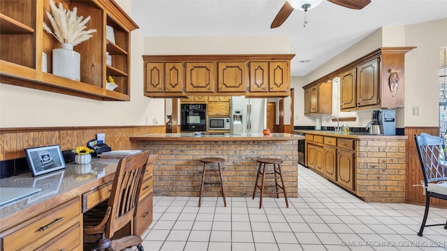 kitchen featuring a breakfast bar, appliances with stainless steel finishes, wooden walls, and light tile patterned flooring