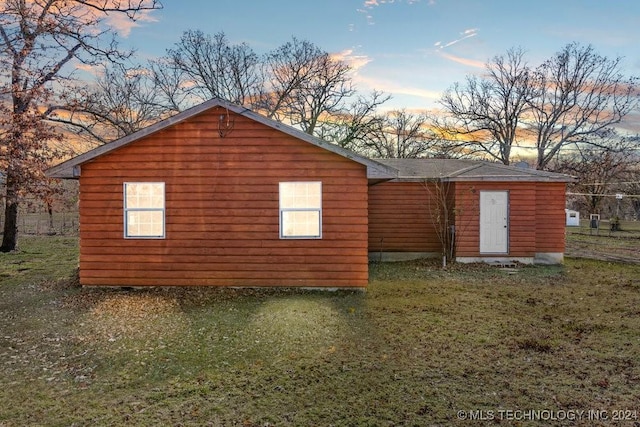 property exterior at dusk featuring a lawn