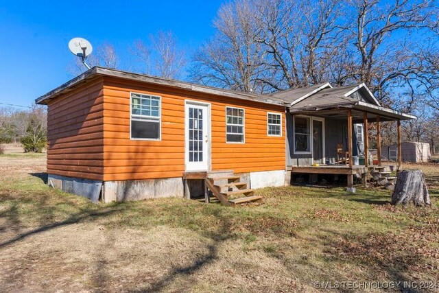 rear view of property featuring a lawn and a porch