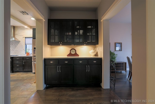 bar with dark hardwood / wood-style flooring, wall chimney range hood, and backsplash