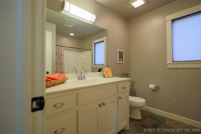 bathroom featuring walk in shower, vanity, toilet, and a wealth of natural light