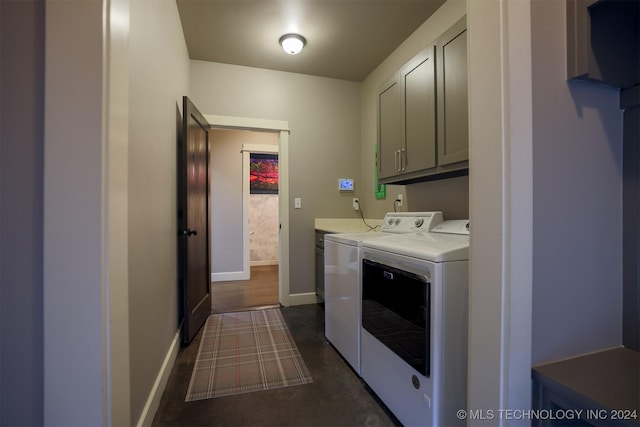 clothes washing area with separate washer and dryer and cabinets