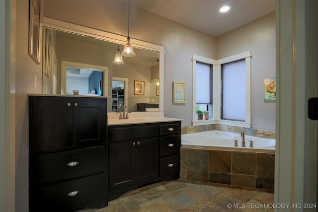 bathroom featuring vanity and tiled tub