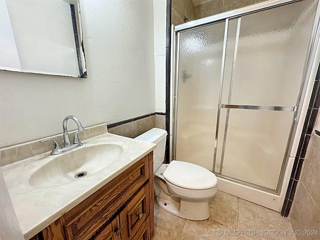 bathroom featuring tile patterned flooring, vanity, toilet, and an enclosed shower