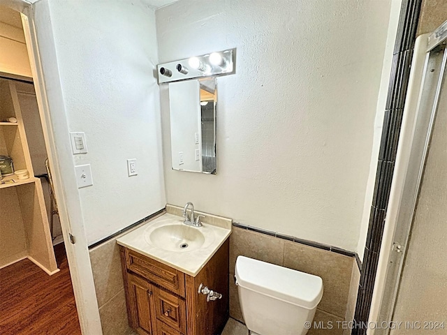 bathroom with vanity, hardwood / wood-style flooring, toilet, and tile walls