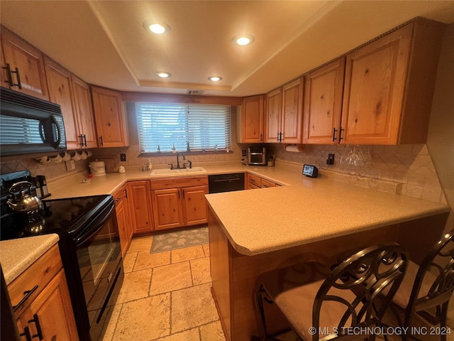 kitchen with kitchen peninsula, a raised ceiling, sink, black appliances, and a breakfast bar area