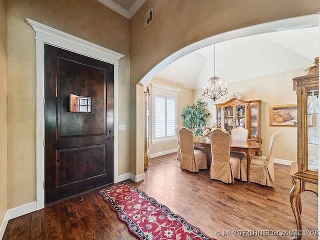 dining area with hardwood / wood-style floors, lofted ceiling, ornamental molding, and a notable chandelier