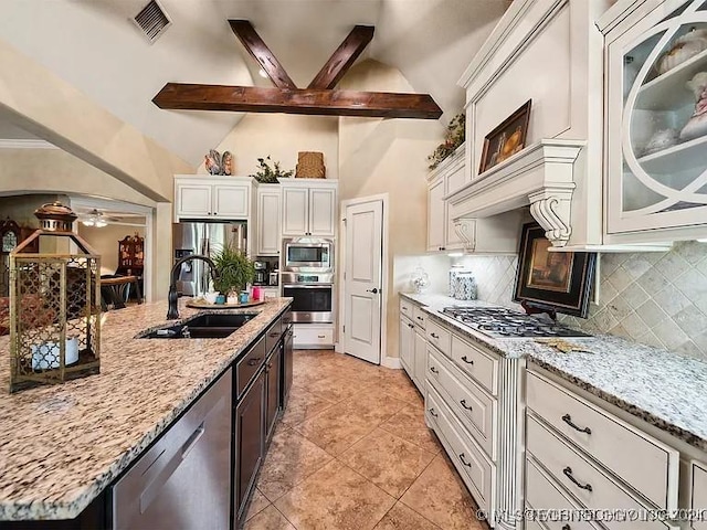 kitchen with backsplash, sink, light stone countertops, beam ceiling, and stainless steel appliances