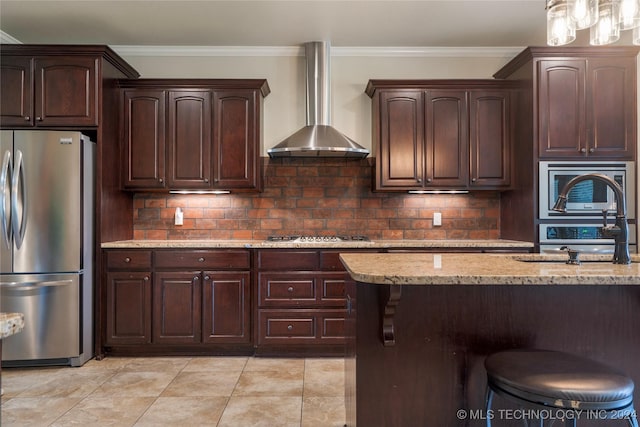 kitchen featuring wall chimney range hood, sink, crown molding, appliances with stainless steel finishes, and light stone counters