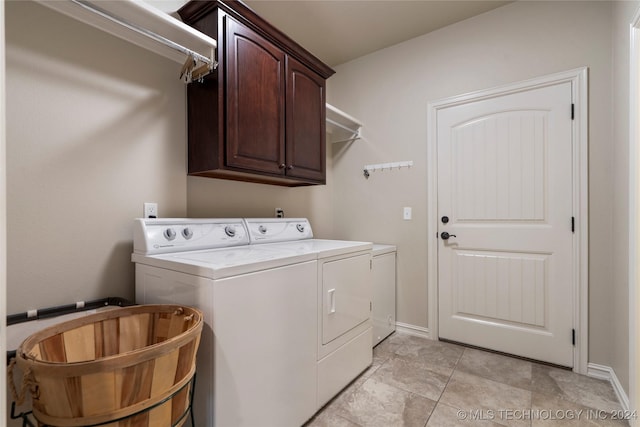 clothes washing area featuring separate washer and dryer and cabinets