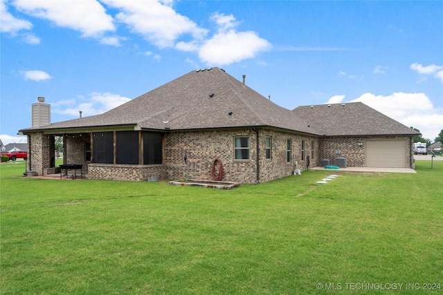 rear view of property with cooling unit, a patio area, a sunroom, a yard, and a garage