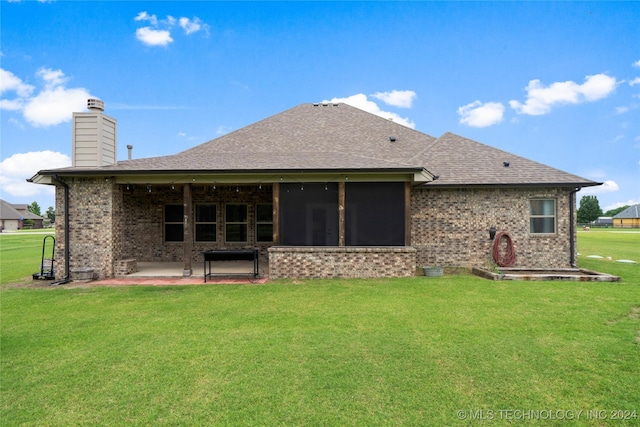 back of property featuring a sunroom, a patio area, and a lawn