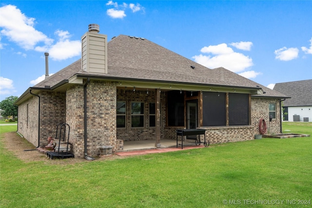 rear view of property featuring a lawn, a patio area, a sunroom, and central air condition unit