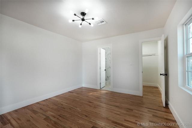 unfurnished bedroom featuring connected bathroom, dark hardwood / wood-style floors, and a notable chandelier