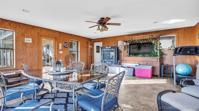 dining room featuring ceiling fan and wood walls