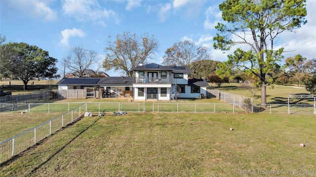 rear view of property with solar panels, a rural view, and a yard