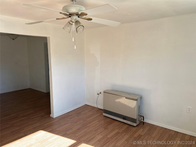 empty room with heating unit, ceiling fan, and wood-type flooring