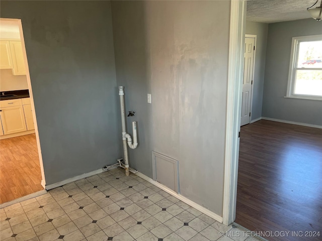 laundry area featuring light hardwood / wood-style floors, sink, and a textured ceiling