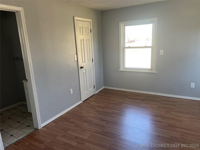 empty room with a textured ceiling and dark wood-type flooring