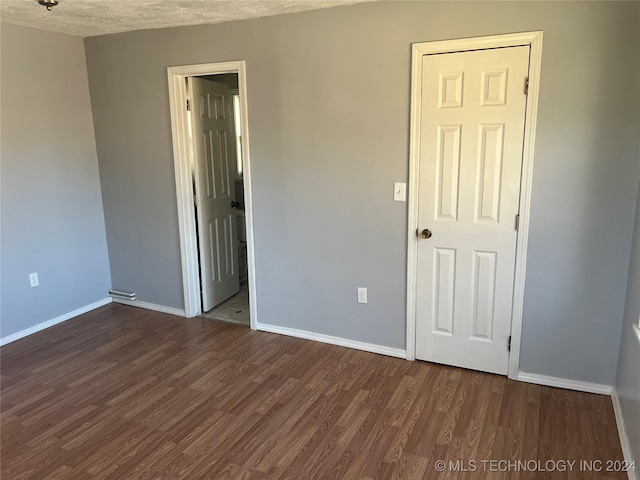 unfurnished room with dark hardwood / wood-style flooring and a textured ceiling