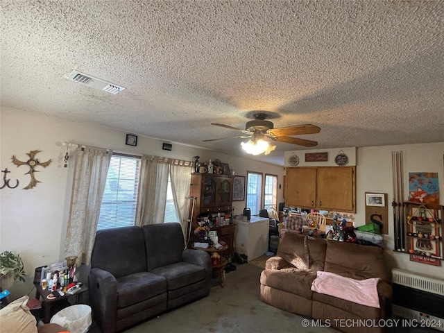 carpeted living room featuring plenty of natural light, ceiling fan, a textured ceiling, and heating unit