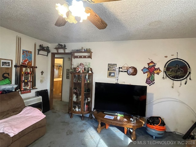 carpeted living room with heating unit, ceiling fan, and a textured ceiling