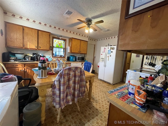 kitchen featuring a textured ceiling, white fridge with ice dispenser, and ceiling fan