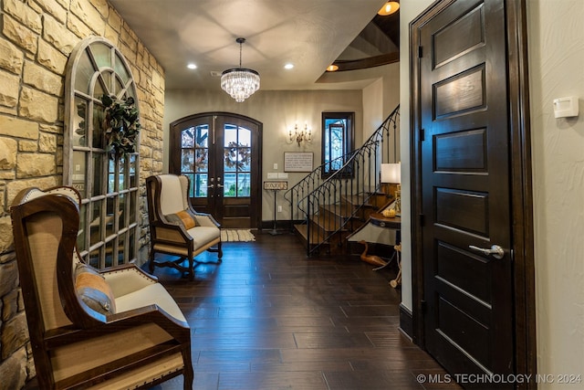 foyer with a notable chandelier, dark wood-type flooring, and french doors