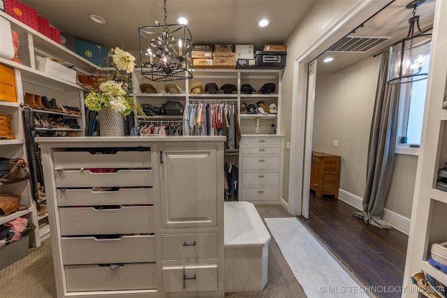 walk in closet with hardwood / wood-style floors and an inviting chandelier