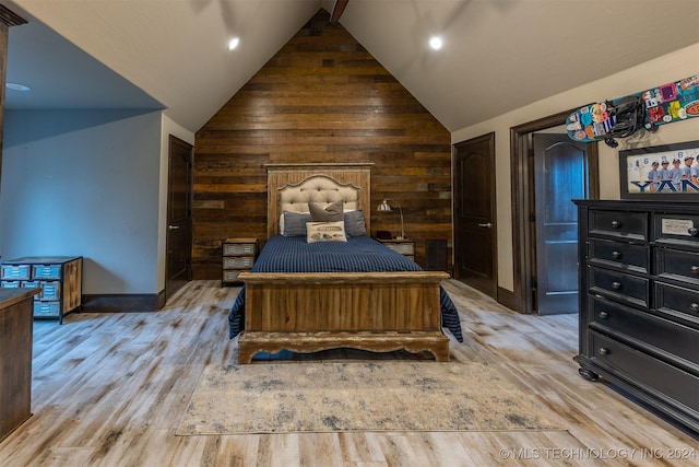 bedroom with wooden walls, vaulted ceiling, and light wood-type flooring