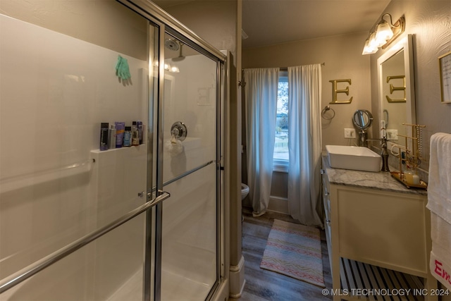 bathroom with hardwood / wood-style floors, vanity, toilet, and walk in shower