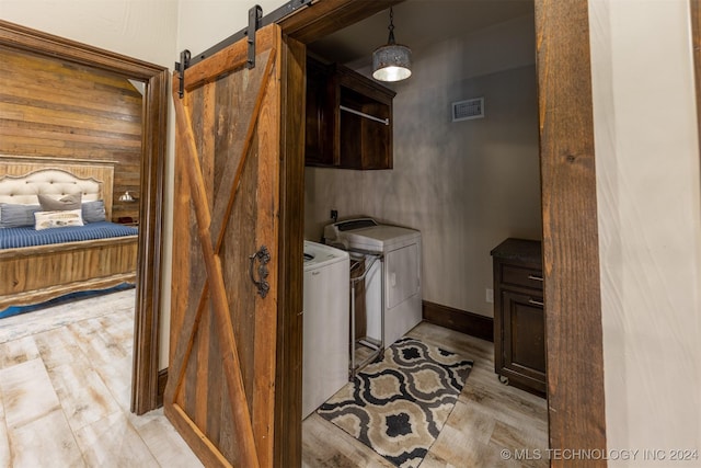 washroom featuring a barn door, cabinets, light hardwood / wood-style floors, and independent washer and dryer