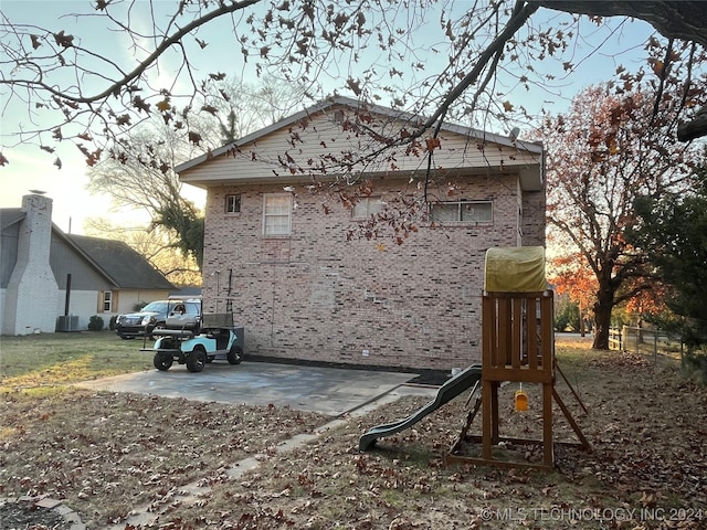 property exterior at dusk with a playground and cooling unit