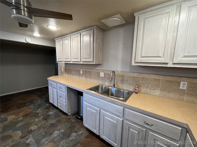 kitchen with tasteful backsplash, white cabinetry, and sink