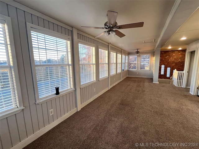 unfurnished sunroom featuring ceiling fan and a healthy amount of sunlight