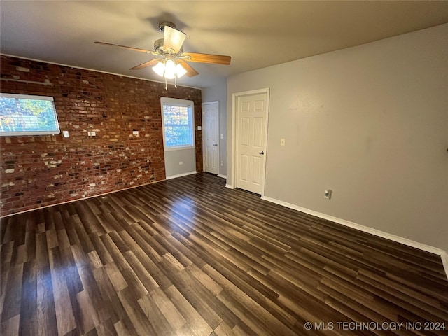 spare room with ceiling fan, dark wood-type flooring, and brick wall