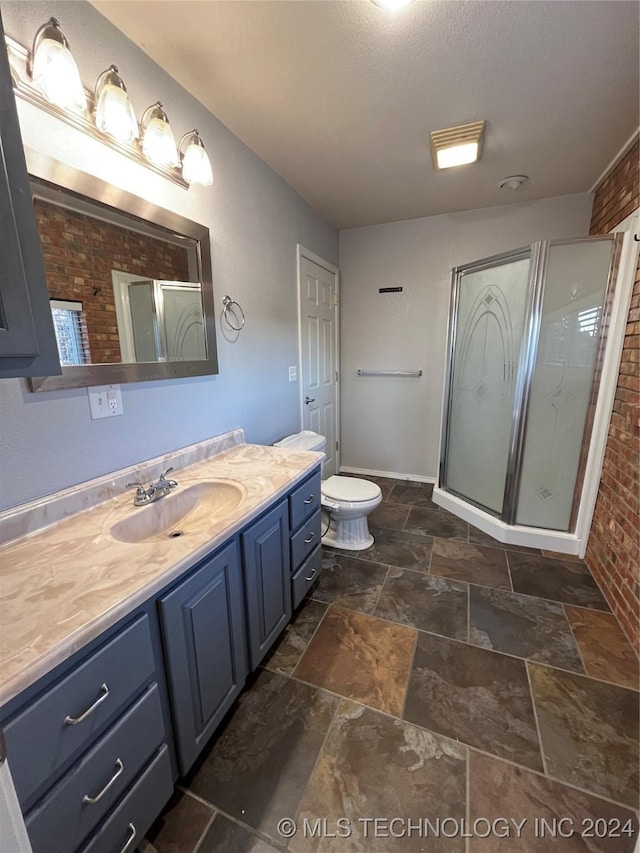 bathroom featuring vanity, toilet, an enclosed shower, and brick wall