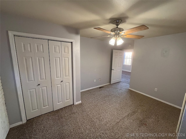 unfurnished bedroom with ceiling fan, dark carpet, and a closet