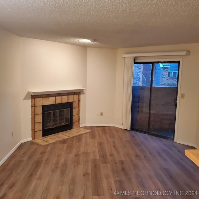 unfurnished living room with hardwood / wood-style floors, a textured ceiling, and a tile fireplace