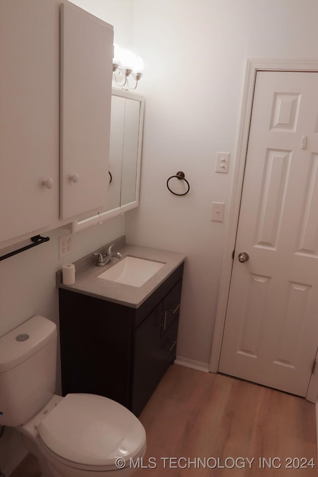 bathroom with hardwood / wood-style floors, vanity, and toilet